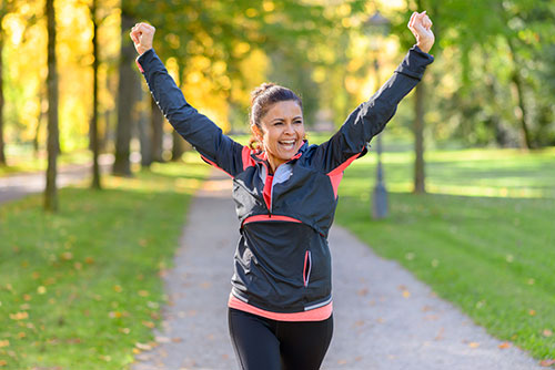 happy and fit woman cheering while running