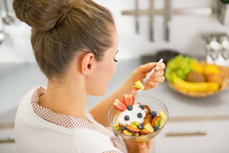 woman enjoying full-fat yogurt and fruit as a weight-loss snack