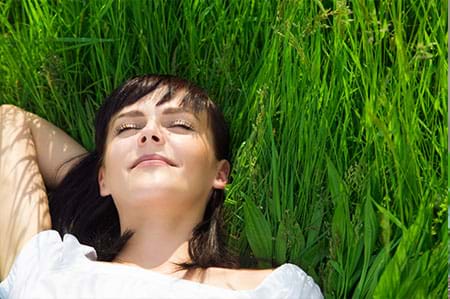woman relaxing and lying in grass happy to be symptom-free