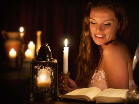 beautiful woman reading an erotic book by candlelight 
