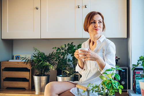 A woman is in the kitchen with herbs for PMS