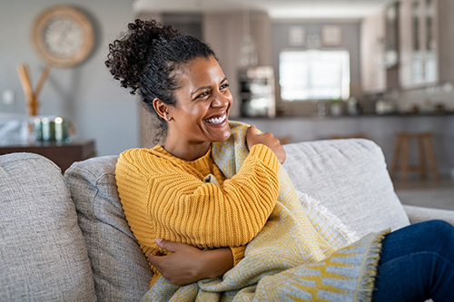 A woman sitting on the couch feeling PMS relief