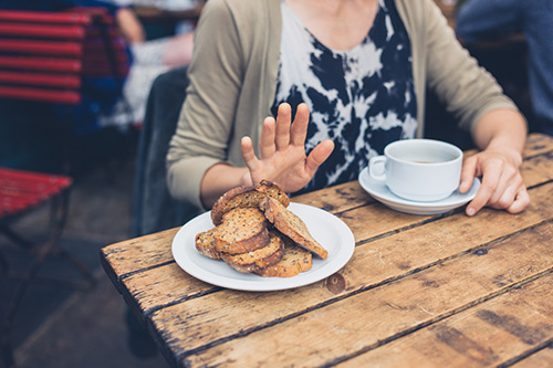 Woman in a cafe refusing gluten containing foods due to her gluten sensitivities