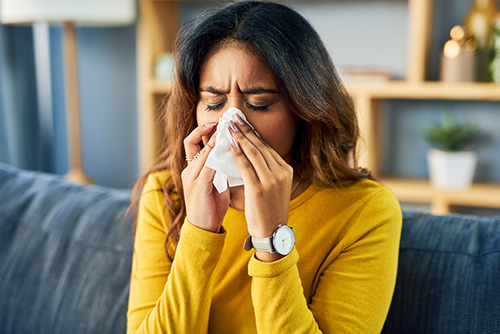 A woman sneezing due to allergies and inflammation