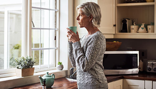 Woman at the window considering the risks of hormone replacement therapy