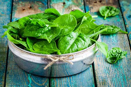 fresh spinach in bowl on wooden table