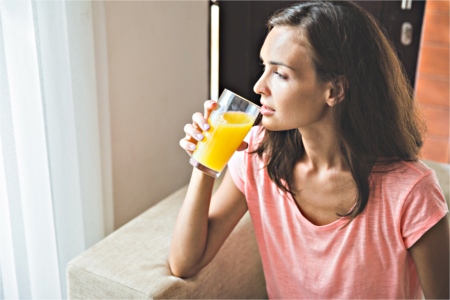 A woman sitting on couch drinking digestive drink. woman sitting on couch drinking digestive drink