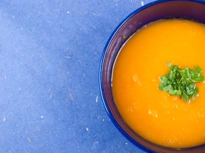 A bowl of pumpkin ginger soup on a blue background. A bowl of pumpkin ginger soup