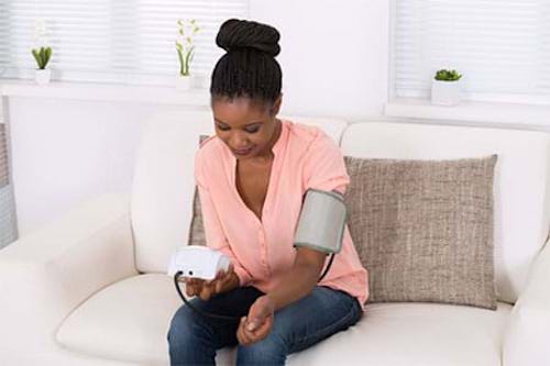 A woman checking her blood pressure to reduce her risk for stroke