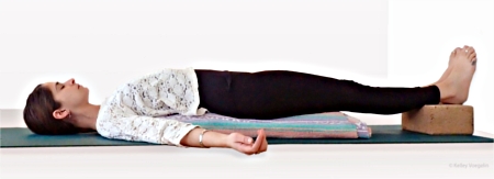 Supported Bridge Pose using a yoga block and blanket