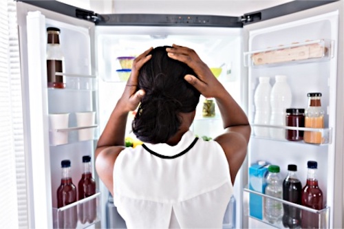 A woman looking into her refrigerator where many nutrients are missing from her diet