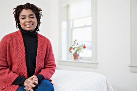 Woman wearing a sweater because she turned down the heat in her home.