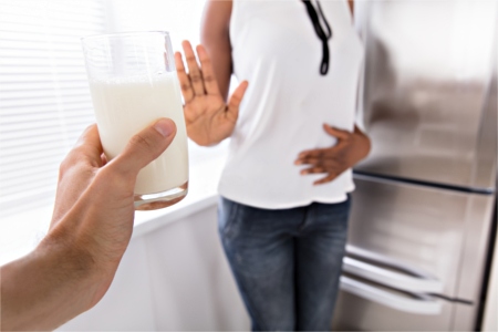 Woman rejecting a glass of milk because of her digestive issues woman saying no to a glass of milk