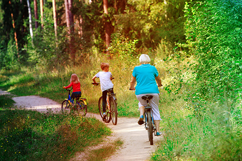 grandmother and two grandchildren riding bikes in woods