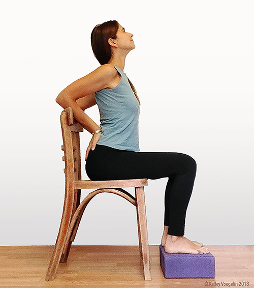 woman doing camel yoga pose modification in chair