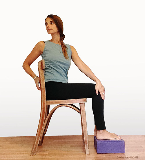 woman doing seated spinal twist yoga pose modification in chair