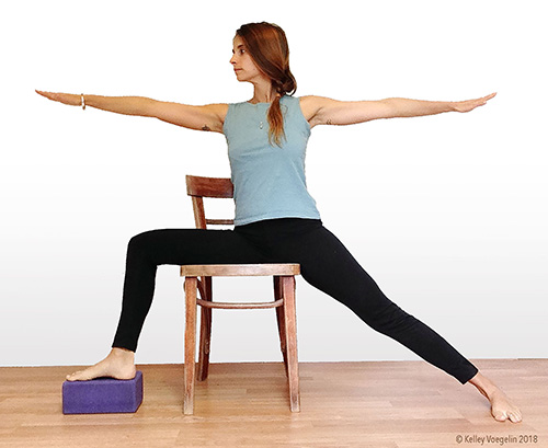 woman doing warrior 2 yoga pose modification in chair