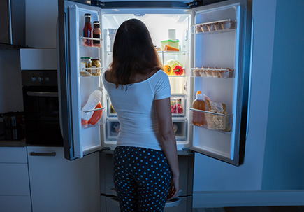 woman looking in the refrigerator for a nighttime snack.
