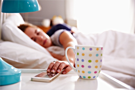 Woman checking mobile phone from bed