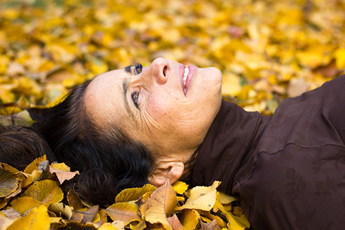 woman daydreaming in pile of fall leaves