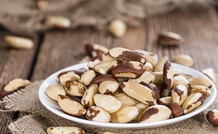 brazil nuts in white bowl a good source of selenium for your thyroid. brazil nuts