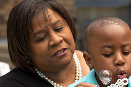 grandmother reducing stress by blowing bubbles with her grandson