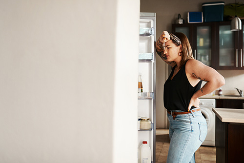 A woman with food cravings looking in the refrigerator