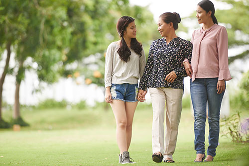 Three generations of women walking in the park talking about how family history is the biggest risk factor for early menopause. three generations of women walking in park talking about early menopause