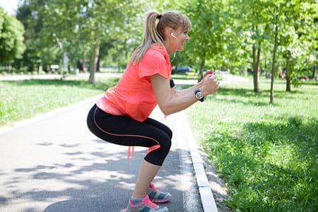 Woman doing squat exercises in the park. Woman doing squat exercises