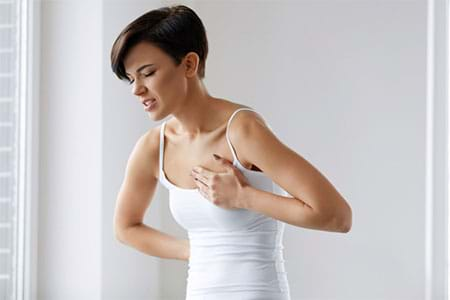 woman holding chest with heartburn