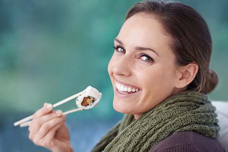 woman smiling at camera eating sushi