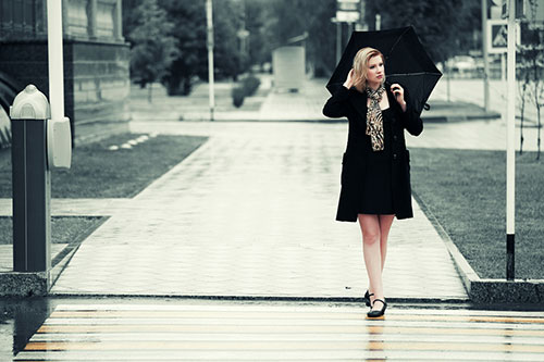 A woman with an umbrella in the rain feeling different symptoms that could be a sign of early menopause. woman with umbrella in rain feeling different symptoms
