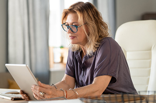 A woman reading while wearing blue light blocking glasses 