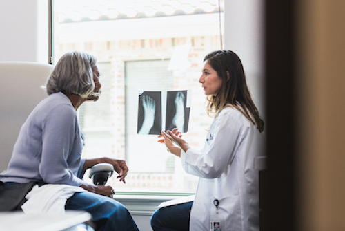 Doctor reviewing fracture X-ray results with a woman. 