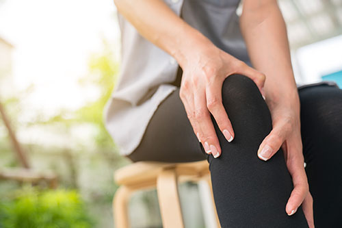 Woman holding her knee in pain with inflammation. 