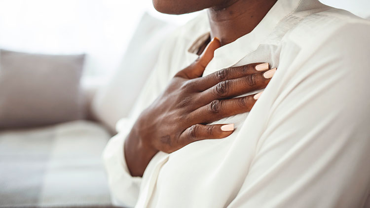 A woman making a heart shape to draw attention to natural heart health for women