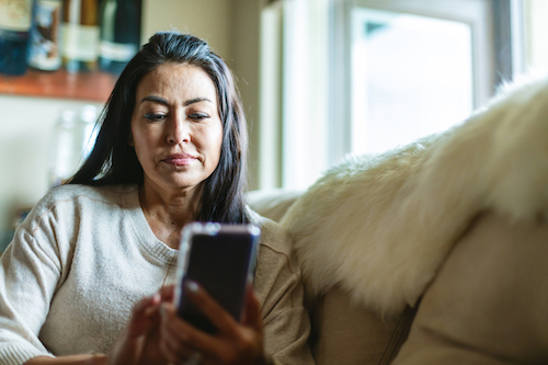 Mature Adult Female Of Hispanic Ethnicity Using Smart Phone In The Home Photo Series